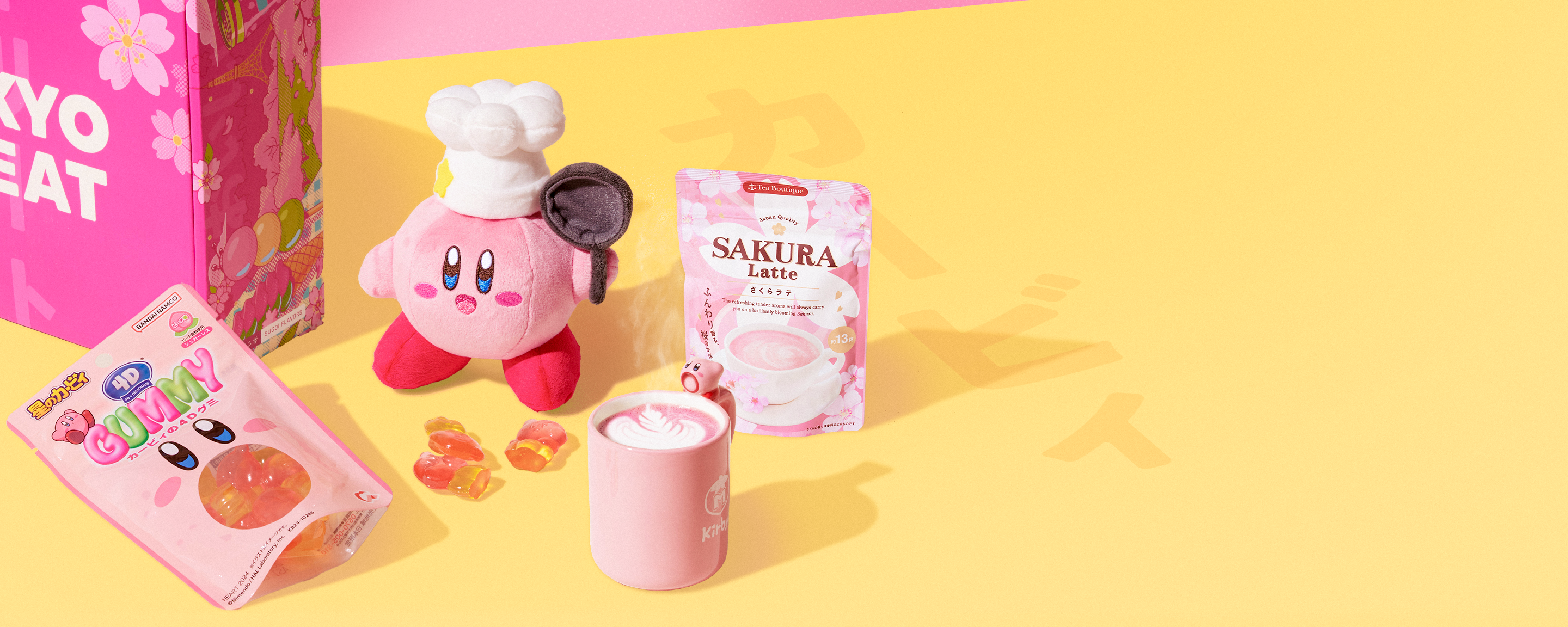 A Kirby mug, plushie, and gummies on a yellow background next to a pack of sakura latte and a sakura TokyoTreat box.