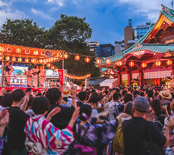 A crowd of festival-goers dance in a circle at a Japanese summer festival.