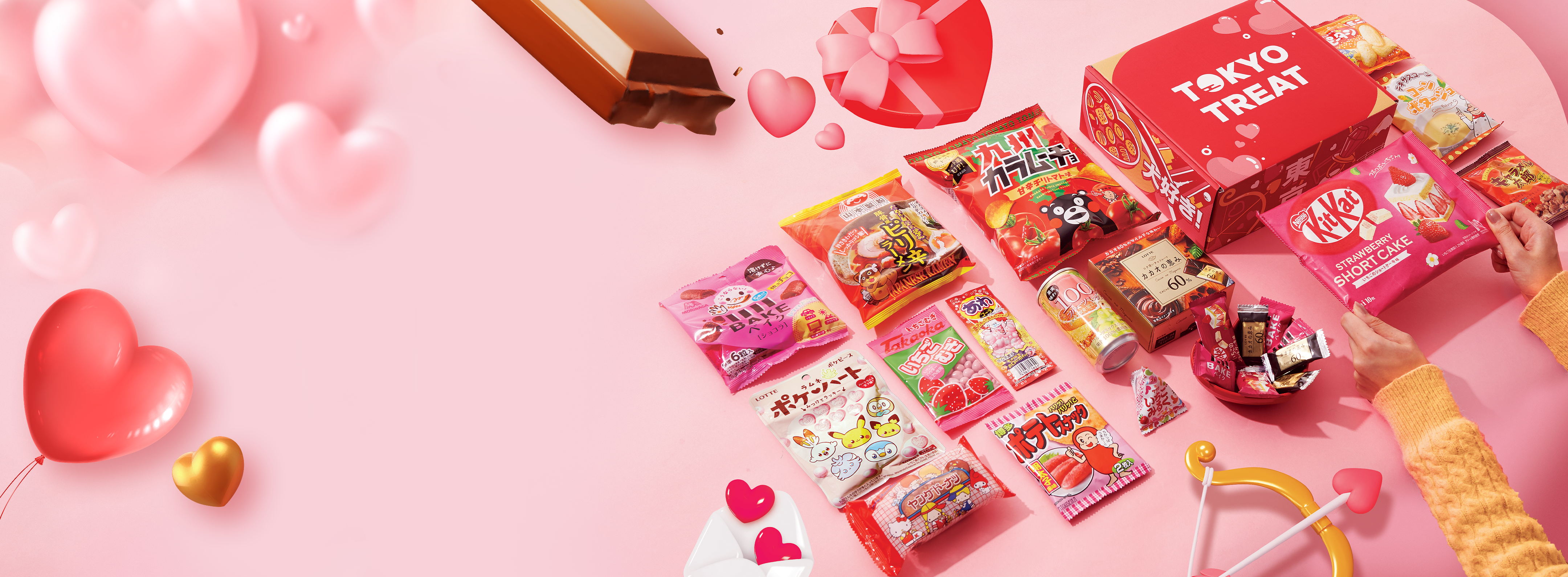 TokyoTreat box sits againt a pink background, surrounded by Valentine items and motifs.