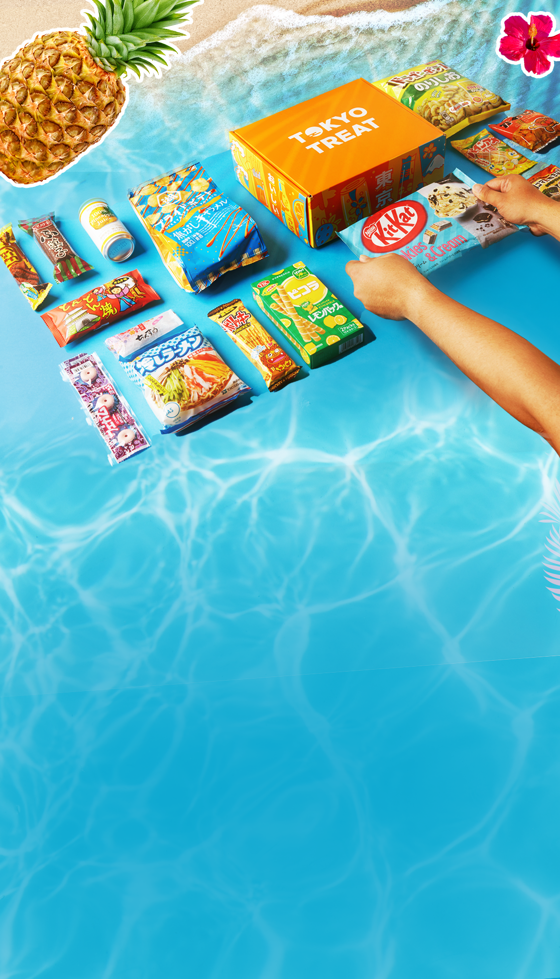 TokyoTreat box sits on a white-sand, blue-water Okinawa beach, surrounded by box items.