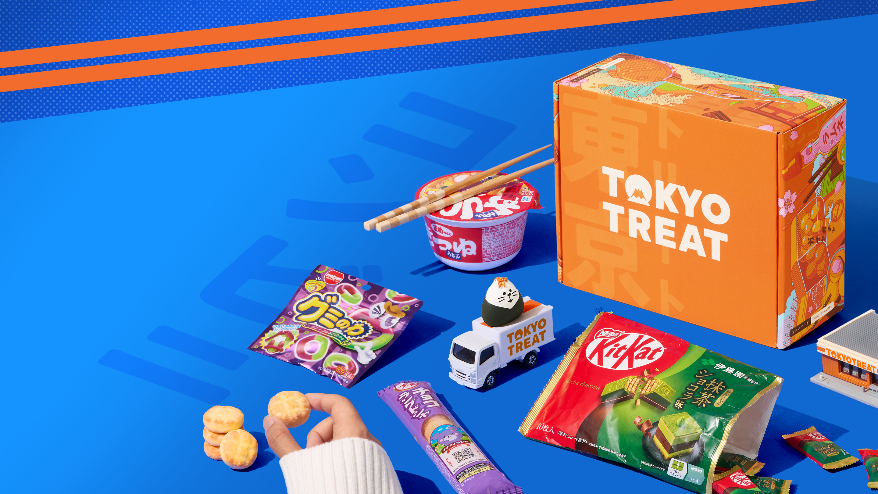 TokyoTreat snack box with konbini-themed snacks around it on a blue background