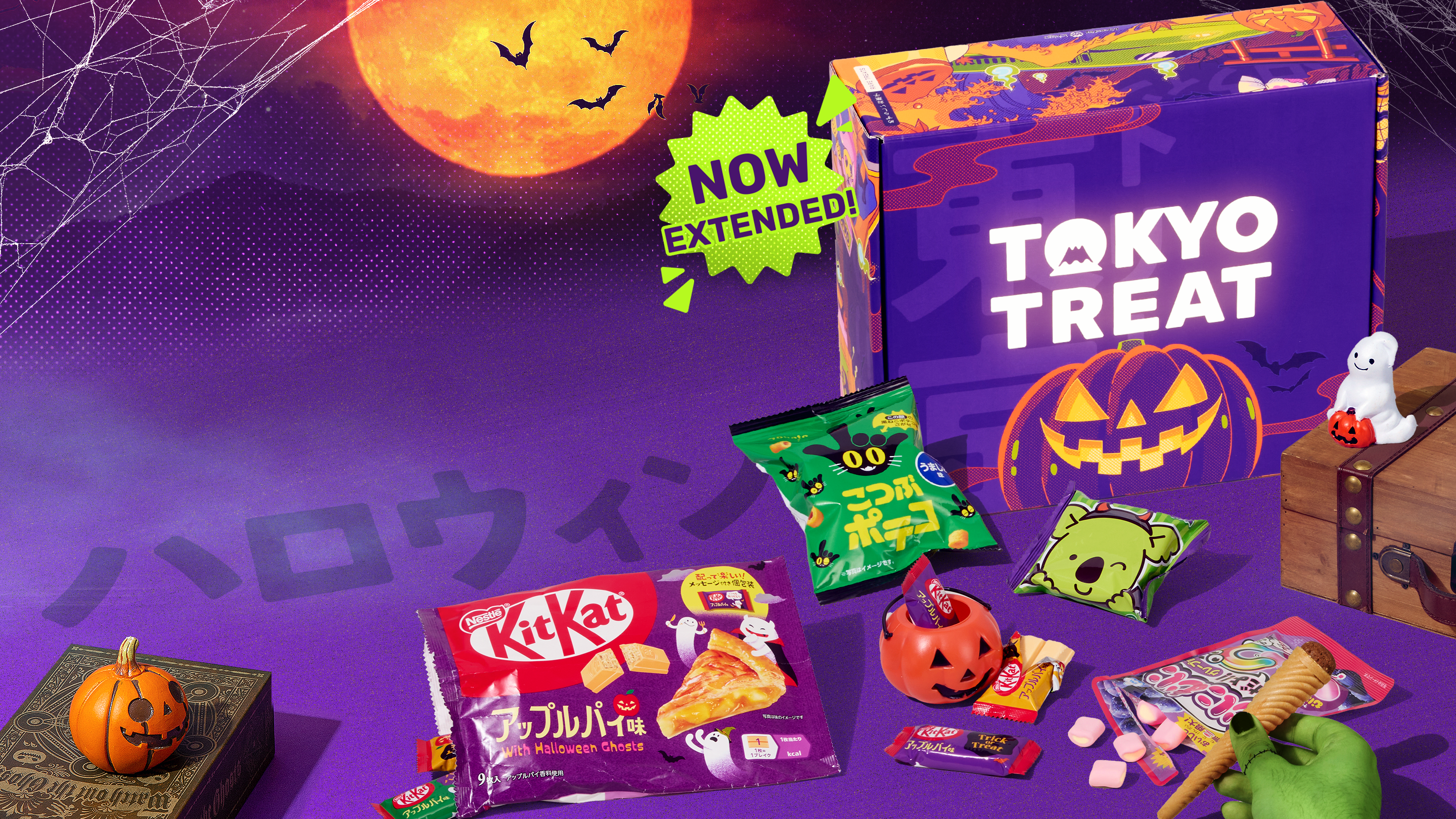 TokyoTreat Halloween box with Halloween-themed snacks around it on purple background with green hand