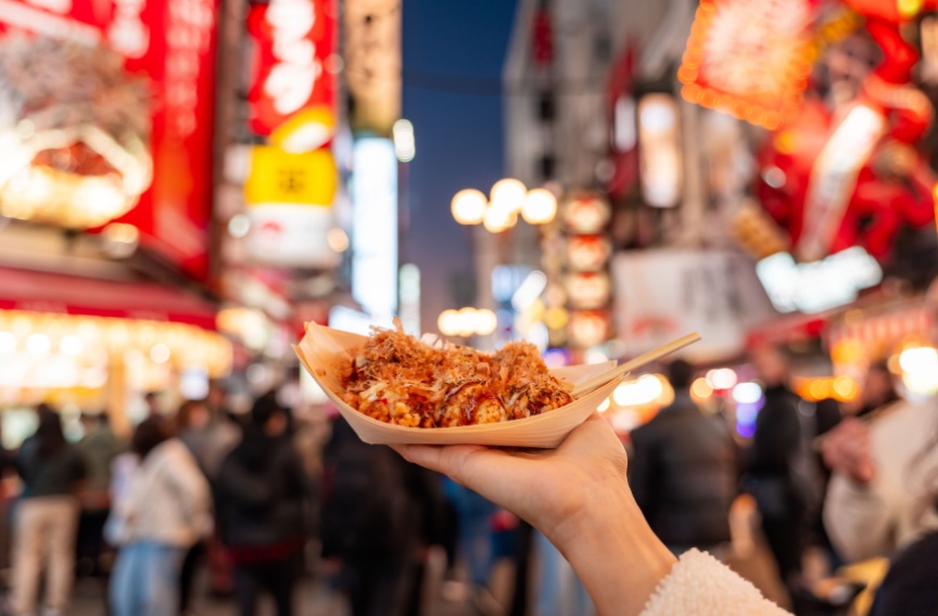 Hand holding a plate of takoyaki in Osaka 
