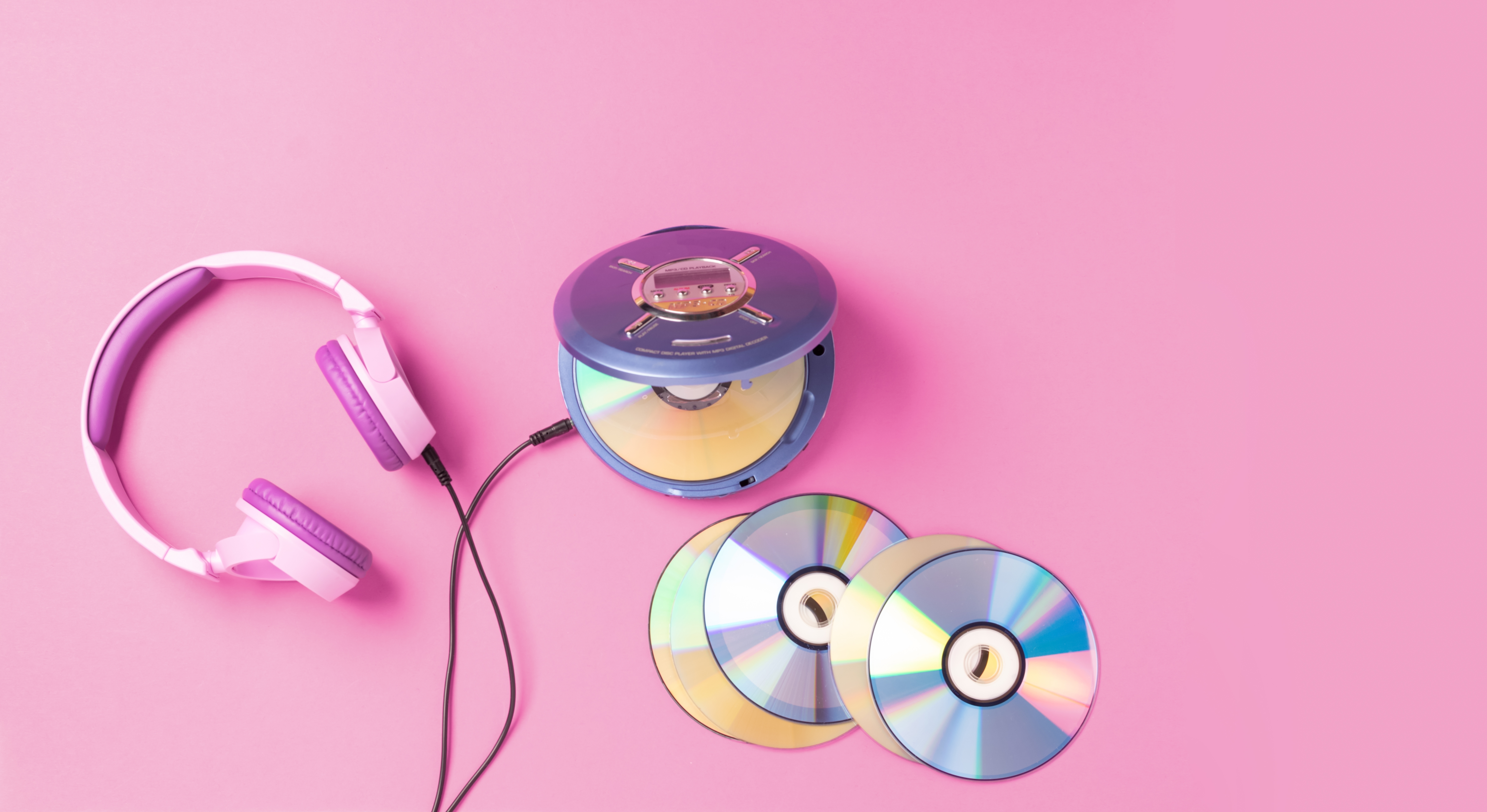 Cd player and headphones on pink background 