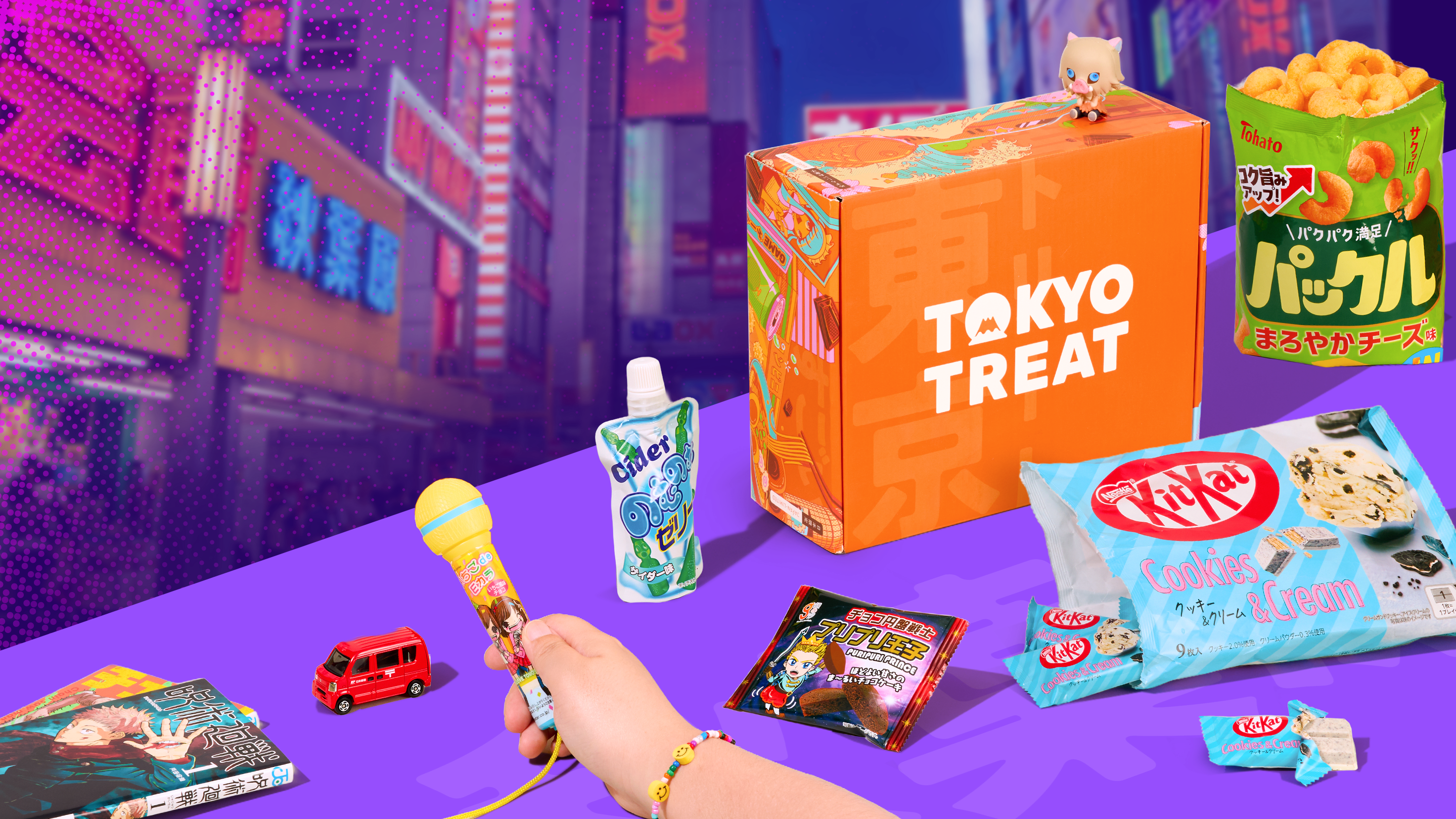 Orange TokyoTreat box with Akiba-themed snacks around it on purple background