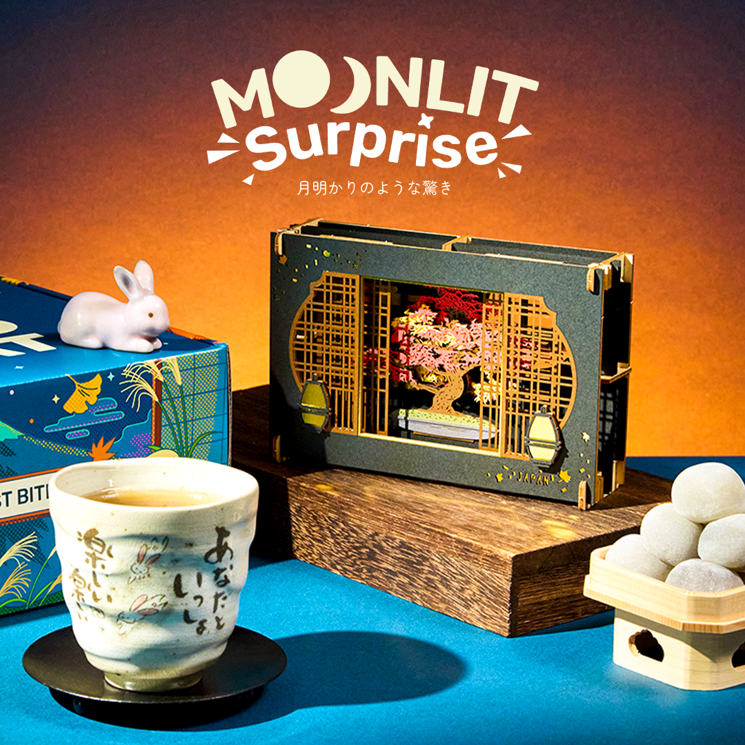 Mochi, papercraft diorama and teacup on a blue and orange background