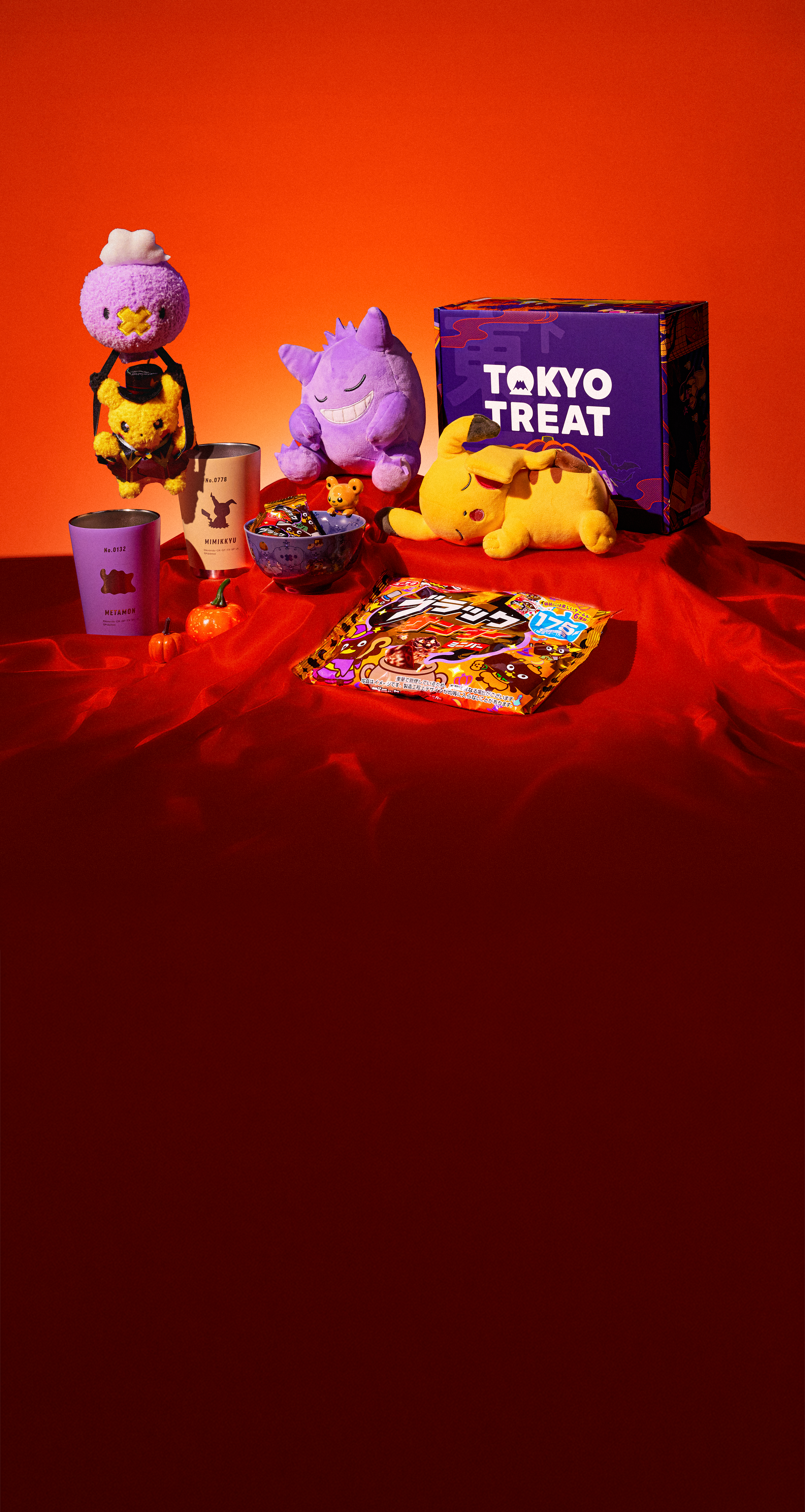 Various Pokémon merch and a violet TokyoTreat box on a red background