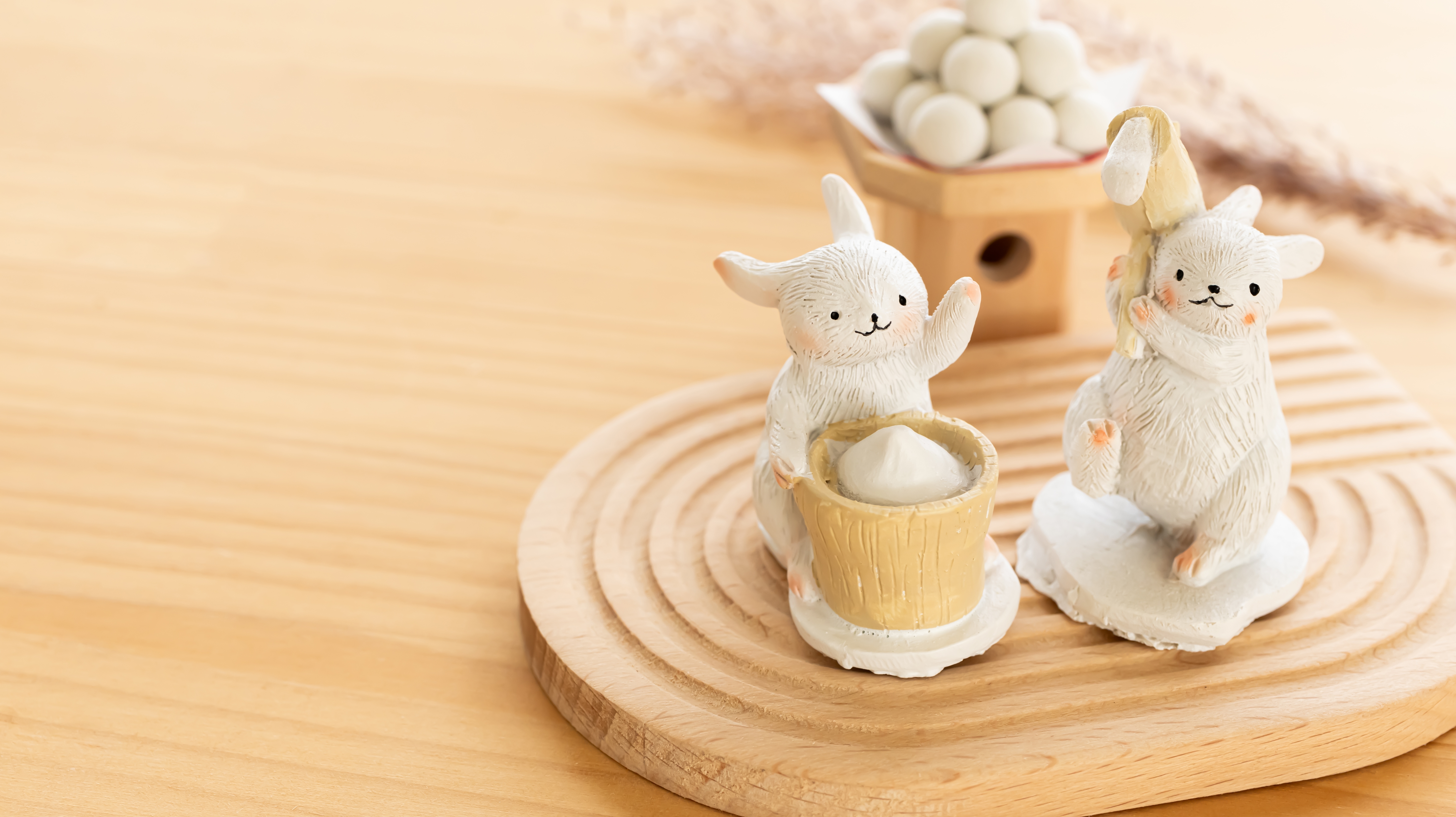Two white rabbits making mochi