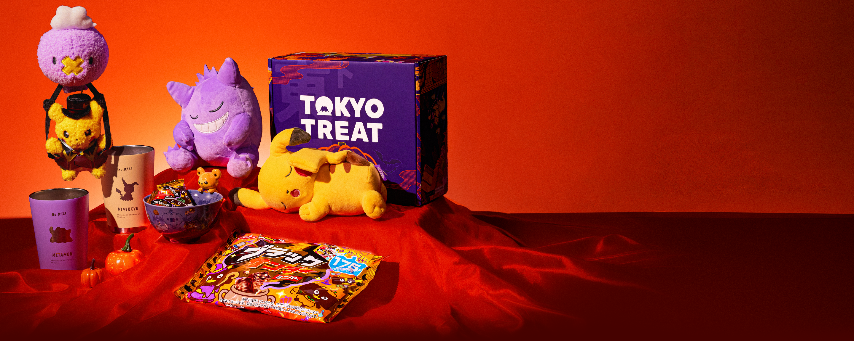 Various Pokémon merch and a violet TokyoTreat box on a red background