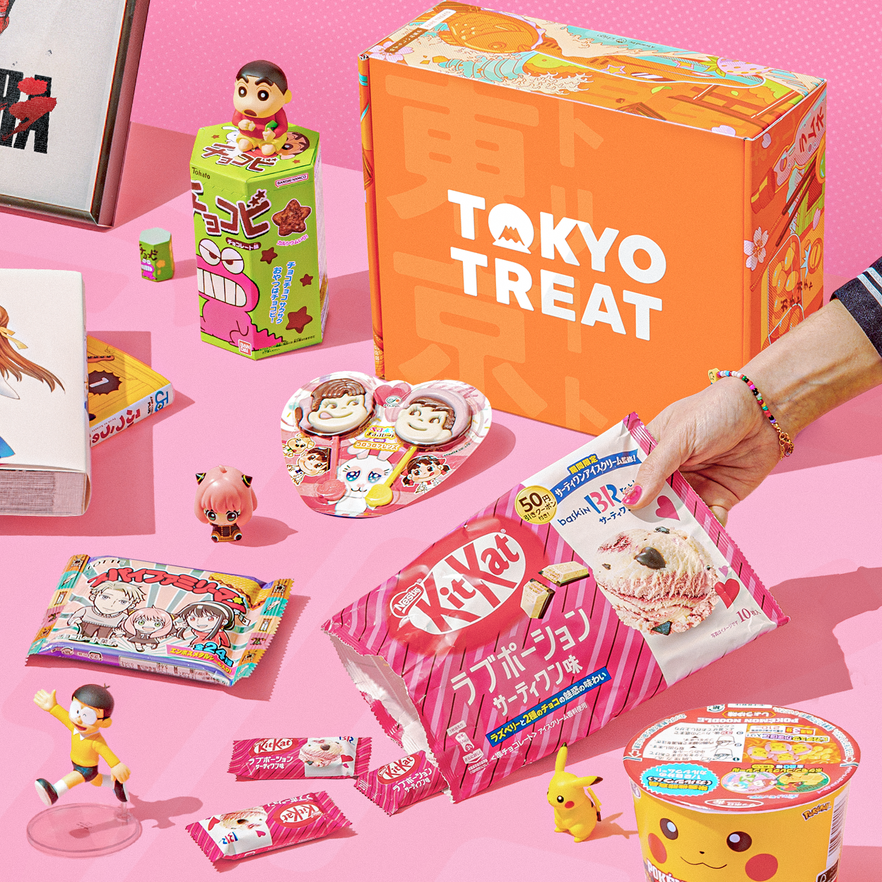 Orange TokyoTreat box with KitKats and fun items on pink background