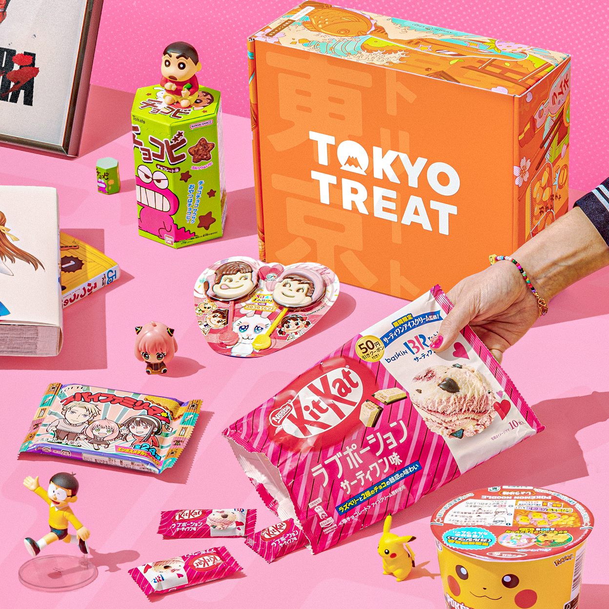 Orange TokyoTreat box with KitKats and fun items on pink background