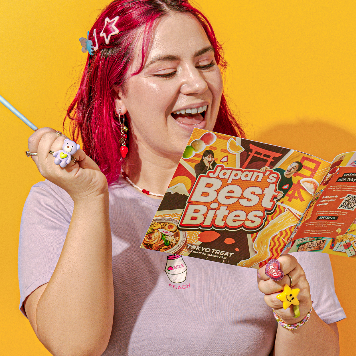 Girl with pink hair reading TokyoTreat booklet