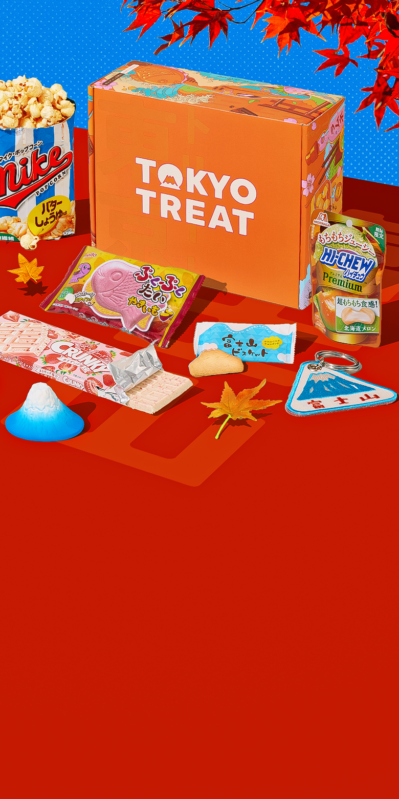 Orange TokyoTreat box with fall snacks around it on red background with Mt. Fuji figurine