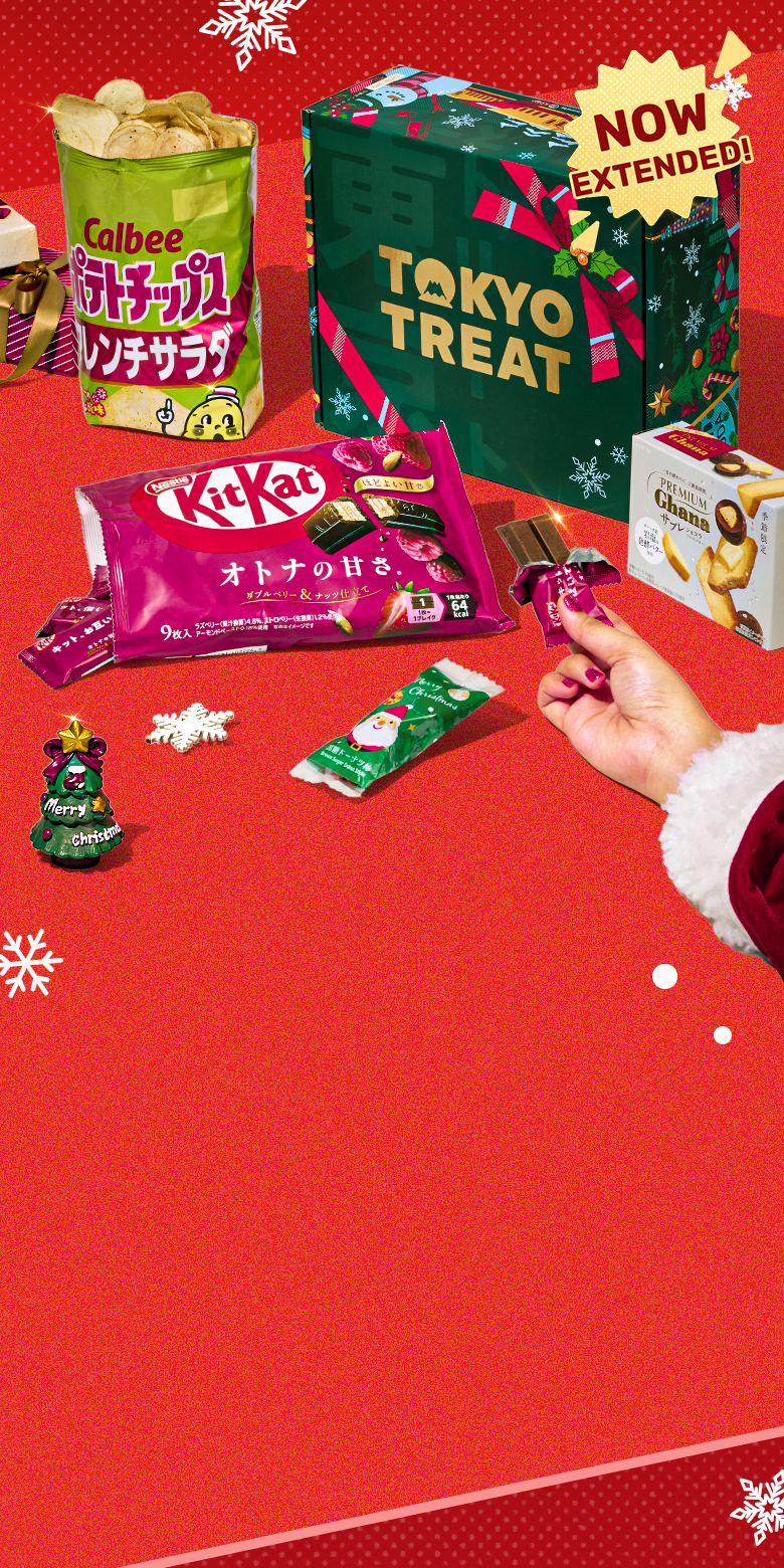 Green TokyoTreat holiday box on red background with snowflake ornament and Christmas themed snacks around it