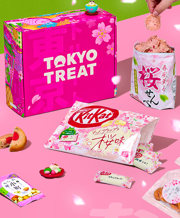 Pink TokyoTreat box with sakura-themed snacks around it on pink background