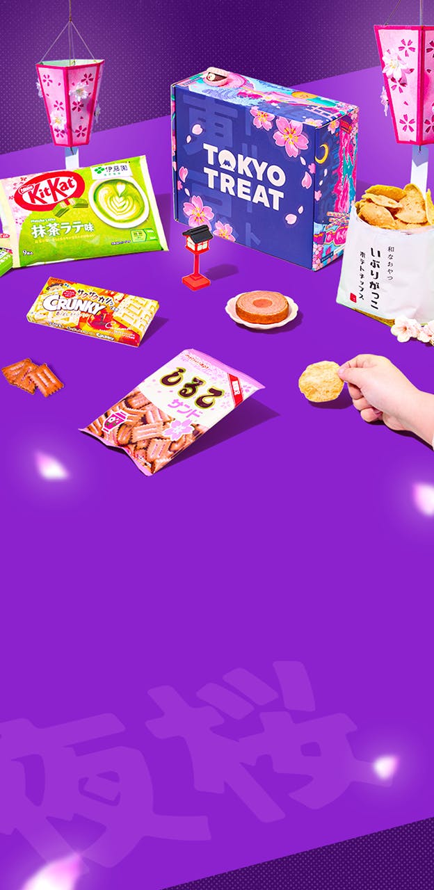 Purple TokyoTreat box with sakura snacks around it and lanterns in the background