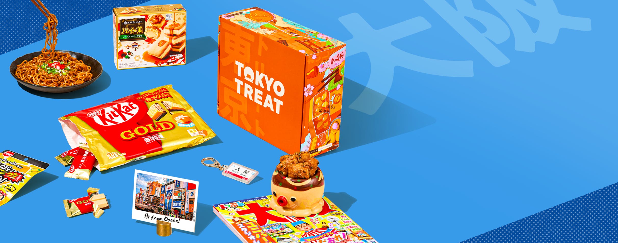 Orange TokyoTreat box with Osaka-themed snacks around it on blue background