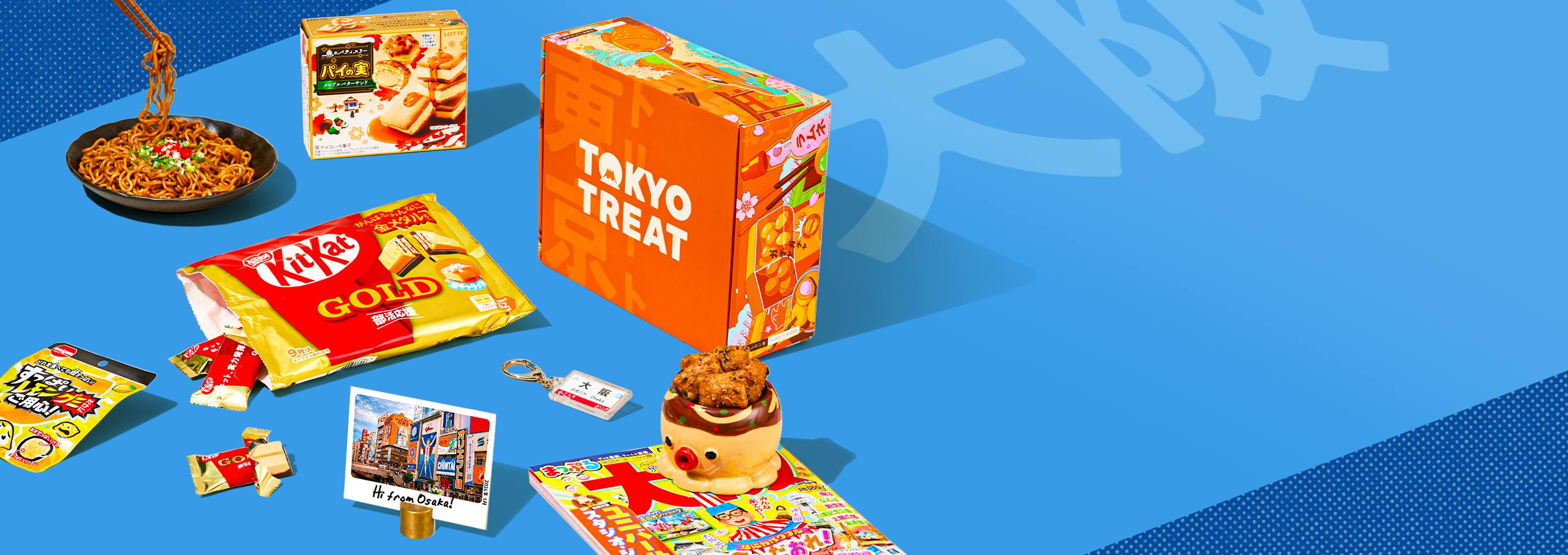 Orange TokyoTreat box with Osaka-themed snacks around it on blue background
