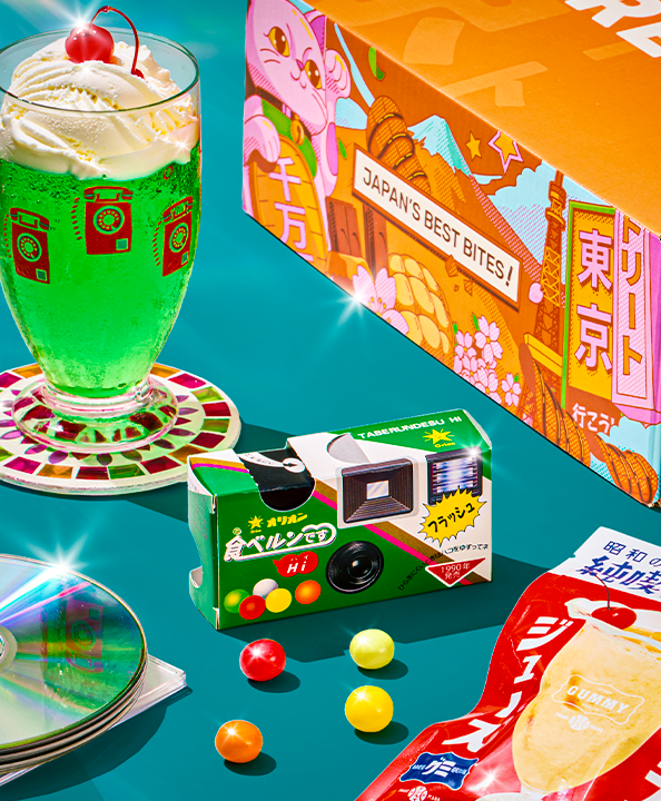 Orange TokyoTreat box with retro snacks on teal background with melon soda float in the back