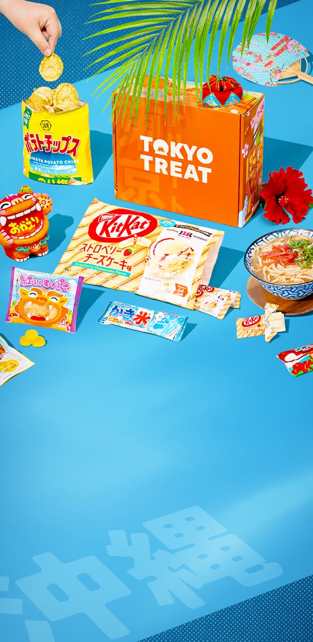 Orange TokyoTreat box on blue background with Okinawa-themed snacks around it