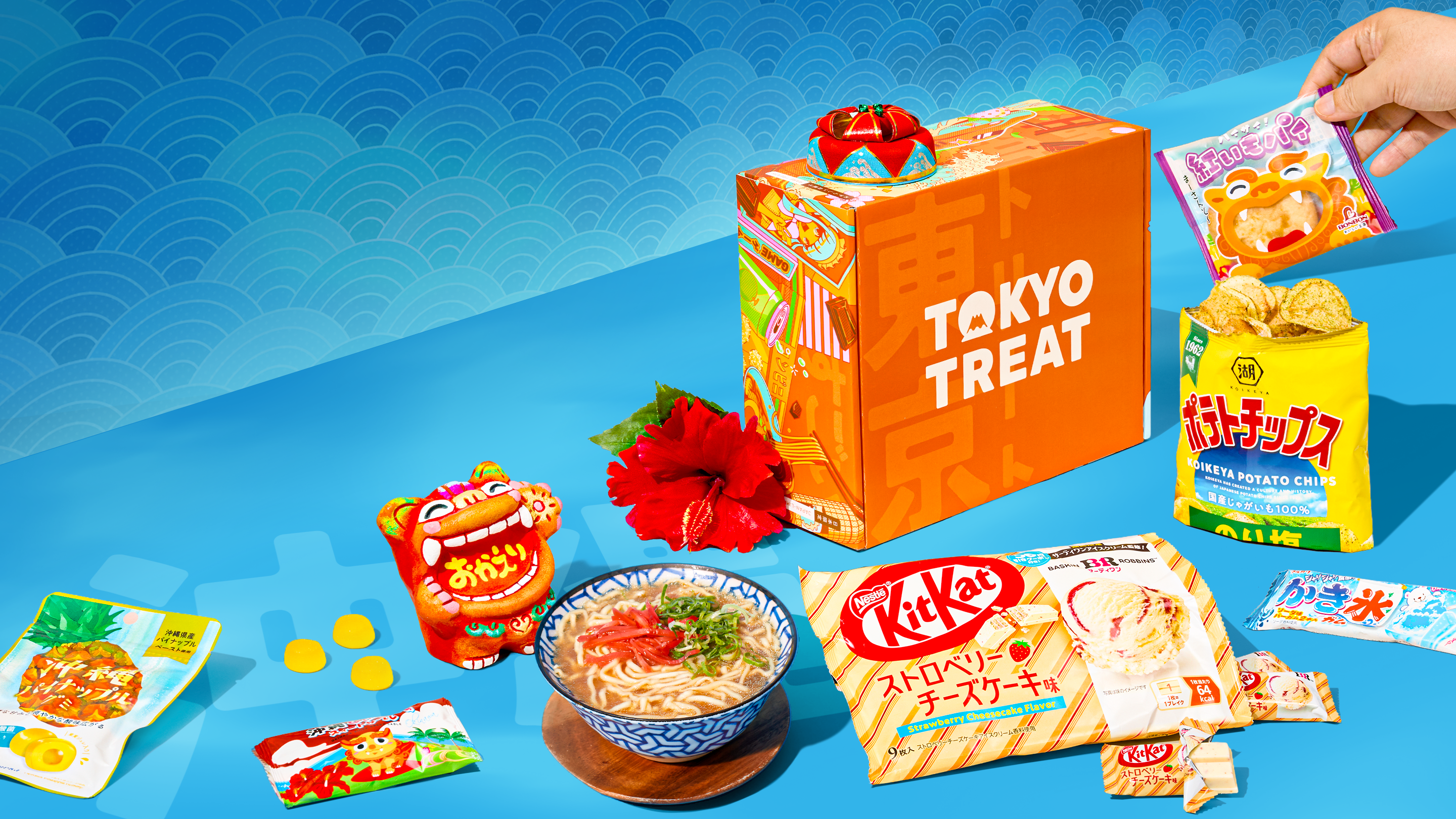 Orange TokyoTreat box with Okinawa snacks around it on a blue background